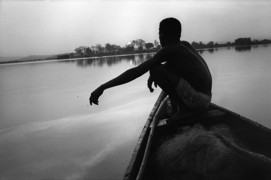 یک ماهیگیر، در غروب، بر روی قایق خود بر روی رود نیجر. باماکو، مالی، ۱۹۹۴.