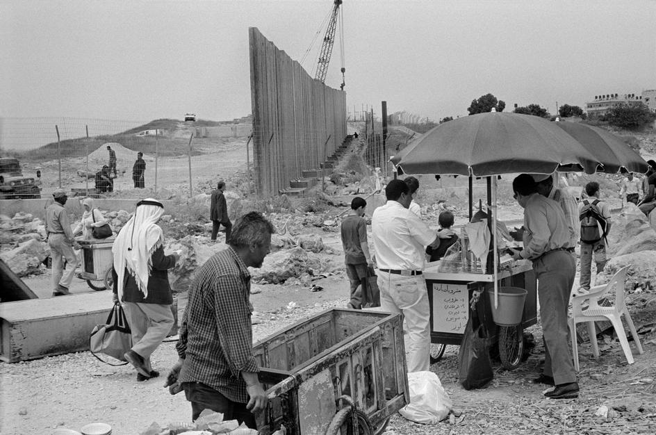 فلسطینیان در محل دیوار در حال ساخت حائل کننده مناطق اشغال شده توسط نیروهای نظامی اسرائیل از فلسطین.