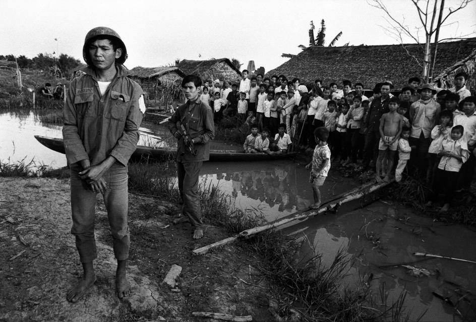 یک سرباز ویتنام شمالی، یک ویتکونگ را به اسرات درآورده و در روستا به نمایش گذاشته است. منطقه دلتای جنوبی، ویتنام، ۱۹۷۳.